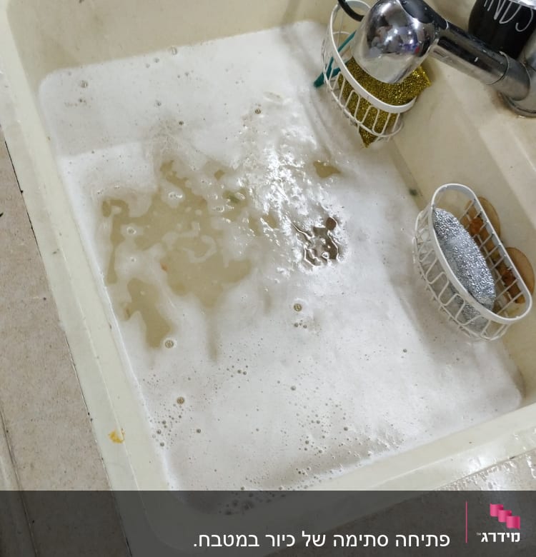 כיור מלא במים מלוכלכים עם סבון וכלי ניקוי